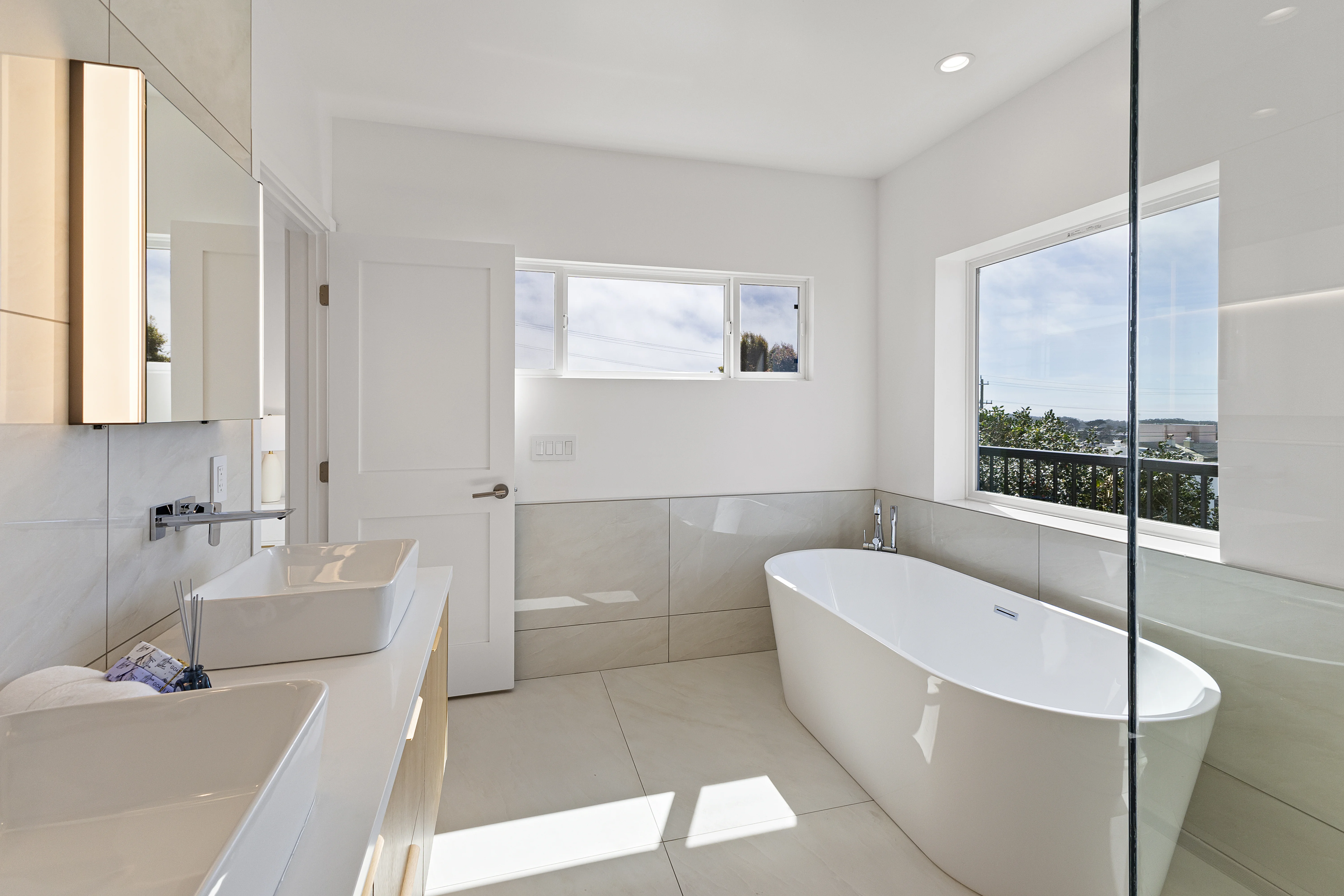 Bright all-white master bathroom with freestanding soaking tub, double vanity and view window