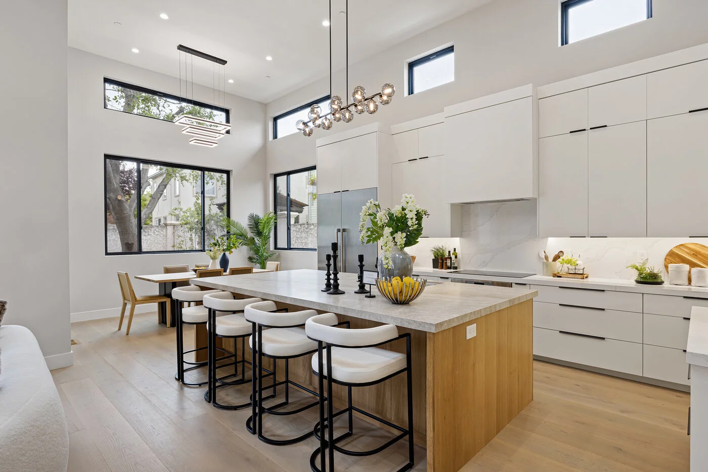 Dramatic open-plan kitchen with two-story windows, oversized island with marble countertop and modern pendant lighting